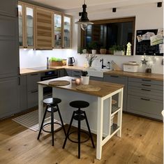 a kitchen with two stools next to an island in the middle of the room