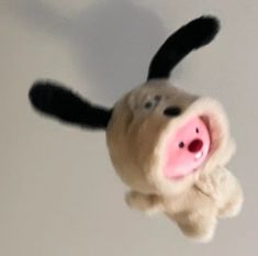 a stuffed animal pig flying through the air with it's nose open and tongue out