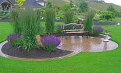 a wooden bench sitting in the middle of a lush green field next to purple flowers