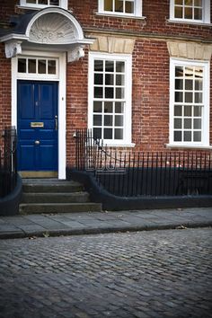 a brick building with white windows and blue door