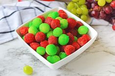 a white bowl filled with green and red candies on top of a marble counter