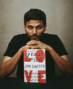 a man sitting at a table with his hands on his chest holding a sign that says rules of love