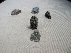 four rocks sitting on top of a sandy ground