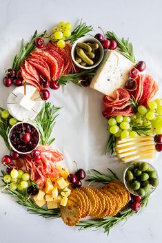 a wreath made out of cheese, crackers, grapes and meats on a table