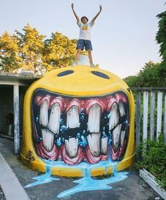 a man standing on top of a giant yellow object with teeth painted all over it