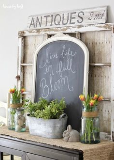 a chalkboard with flowers in vases and an old window frame as a sign