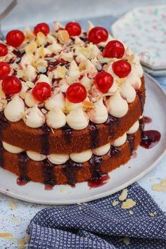 a cake with cherries on it sitting on a plate next to a blue napkin