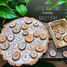 a wooden board with letters and numbers on it next to a tray full of wood slices