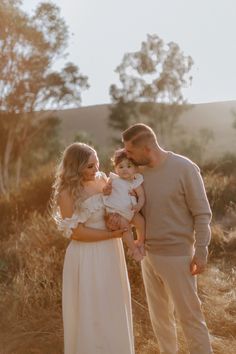 a man and woman holding a baby in their arms while standing next to each other