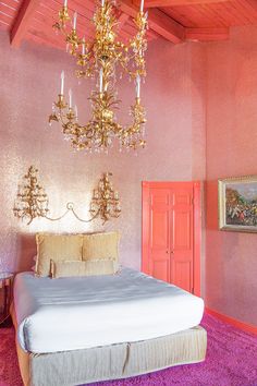 a bedroom with pink walls and a chandelier hanging from the ceiling