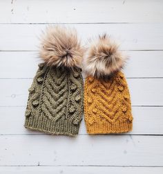 two knitted hats with pom - poms on them