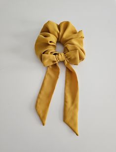 a yellow scarf tied to a white wall with a knot in the middle on it