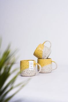 three yellow and white coffee mugs sitting next to each other on top of a table