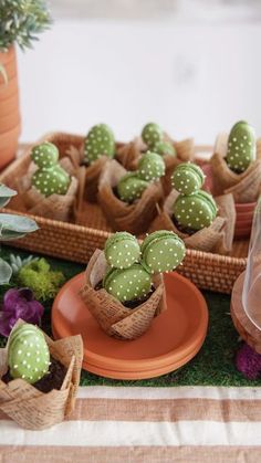 small cactus plants are in baskets on the table with plates and bowls full of succulents