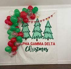 a christmas banner hanging on the wall next to balloons and streamers that read, pha gamma delta christmas