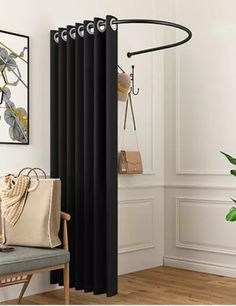 a room with white walls and wooden floors, black curtains are hanging on the wall