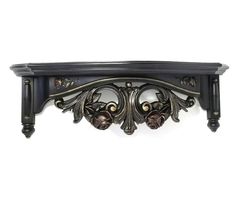 a black shelf with ornate carvings on the top and bottom, against a white background