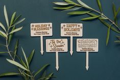 three wooden signs with the words holiday holidays on them next to some green leaves and branches