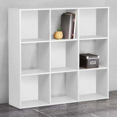 a white book shelf with books on top and some other items next to it in front of a wall