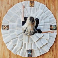 a woman laying on top of an open book covered in pages with her arms stretched out