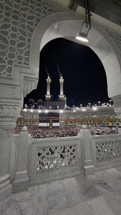 a large group of people standing in front of a building at night with lights on