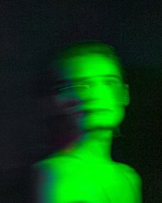 a blurry image of a man with glasses on his head and green light in the background