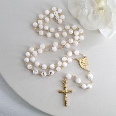 This Personalized Rosary, is ideal as a Baptism gift for a little girl or baby boy or as a gift for a special occasion. It is expertly handcrafted in a traditional style with a contemporary twist utilizing genuine Mother of pearl stone and gold-plated brass wire, which not only gives a touch of nature but also tenderness. The letter beads on the Rosary are also handmade from genuine mother of pearl, and the length is perfect to worn as a dainty Rosary necklace for women. *MATCHING ROSARY BRACELE White 8mm Beads Jewelry As Gift, White Jewelry With 8mm Beads For Gift, White Jewelry With 8mm Beads As Gift, Beaded Cross Jewelry For First Communion, Cross-shaped Beaded Jewelry For First Communion, Handmade White Rosary Bracelet For Wedding, White Beaded Rosary Bracelet For Gift, Elegant White Rosary For First Communion, Pearl White Rosary With 8mm Beads As Gift