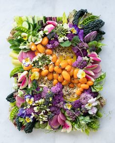 an arrangement of flowers and fruits arranged in the shape of a square on a white surface