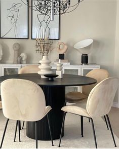 a dining room table with chairs and vases on top of it in front of two framed pictures