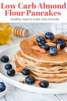 a stack of pancakes topped with blueberries and nuts on top of a white plate