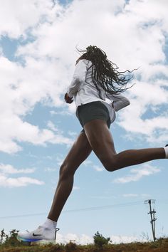 a woman is running in the air with her hair blowing back and legs spread out