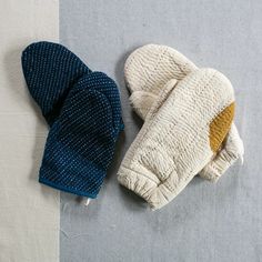 two oven mitts sitting on top of a table next to each other, one has a blue and white mitt