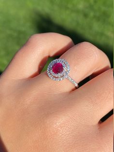 The Titania Double Halo Ruby and Diamond Ring in 14 Karat White Gold. This contemporary cocktail ring centers on a 1.05 carat ruby. The ruby is encircled by a double diamond halo with diamonds continuing down either side of the shank. The mounting has 0.58 total carats of diamonds. This modern ring is a finger size 6 3/4, yet can be adjusted to any size. Each piece has been hand selected and meticulously identified and graded by a Graduate Gemologist who has been awarded a degree by the Gemologi Gia Certified Round Cut Ruby Ring Fine Jewelry, Gia Certified Round Cut Ruby Ring, Dazzling Gia Certified Ruby Ring, Ruby Ring With Diamond Cluster And Brilliant Cut, Cluster Ruby Ring With Brilliant Cut Diamonds, Red Diamond Cluster Ring With Halo Setting, Cluster Ruby Ring With Center Stone, Elegant Gia Certified Lab-created Ruby Rings, Cluster Ruby Diamond Ring With Center Stone