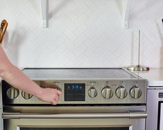 a person pulling something out of an oven with their hand on the door handle and in front of it