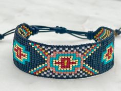 Introducing our southwestern cross cuff bracelet- perfect for adding a touch of boho chic to any outfit! This bracelet is handmade with black leather trim and colorful seed beads, and features an adjustable closure for a perfect fit. It is beaded on strong beading thread & flexible natural leather for comfortable stylish look. It can be worn alone or stacked with other pieces. 7/8 of an inch wide. This bracelet will fit a 6-8 inch wrist. When you purchase this bracelet, I make it to order, just Adjustable Black Cuff Bracelet With Colorful Beads, Bohemian Beaded Bracelets With Adjustable Band, Bohemian Multicolor Beaded Bracelets With Adjustable Band, Bohemian Multicolor Beaded Bracelet With Adjustable Band, Adjustable Black Bohemian Beaded Bracelets, Artisan Black Beaded Bracelets With Colorful Beads, Artisan Adjustable Black Cuff Bracelet, Black Bohemian Resizable Friendship Bracelets, Handmade Southwestern Black Beaded Bracelets