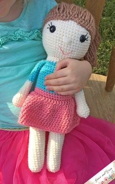 a crocheted doll is sitting on a pink tutu skirt and holding it in her hands