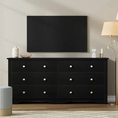 a living room with a large television mounted on the wall next to a black dresser