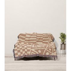 a brown and white blanket sitting on top of a wooden floor next to a potted plant