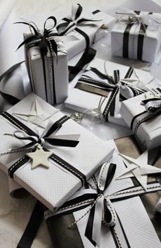 many wrapped gift boxes with black and white ribbons