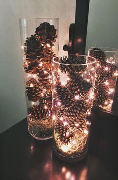 two glass vases filled with pine cones on top of a table