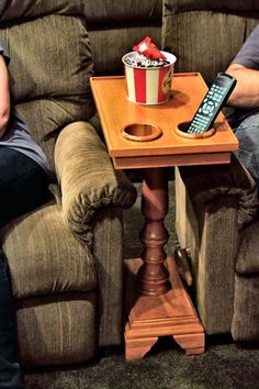 two people sitting on couches with remotes and a table in front of them