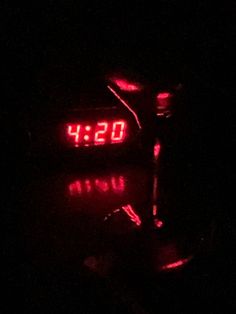 the clock is lit up in the dark with red light on it's face