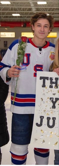 two people standing next to each other holding flowers and a sign that says thank you junior