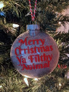 a christmas ornament that says merry christmas ya filthy animal hanging from a tree