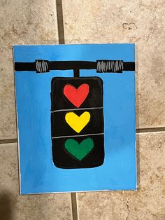 a child's hand is holding up a piece of art that looks like a traffic light