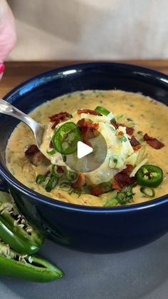 a blue bowl filled with soup sitting on top of a table next to green peppers