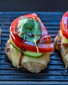 two sandwiches with tomatoes, lettuce and cheese on them sitting on a grill