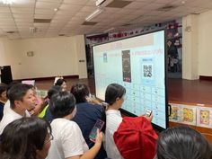 a group of people standing in front of a projector screen while holding cell phones