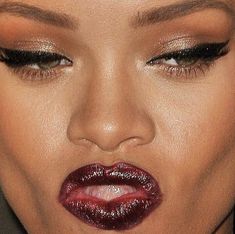 a close up shot of a woman's face with red lipstick and gold eyeshadow