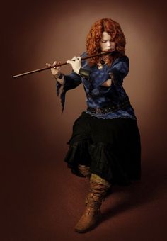 a woman with red hair is holding a stick